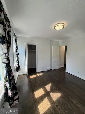 an empty room with wooden floor cabinet and a window