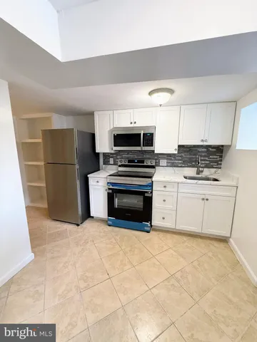 a kitchen with granite countertop a stove a sink and a refrigerator