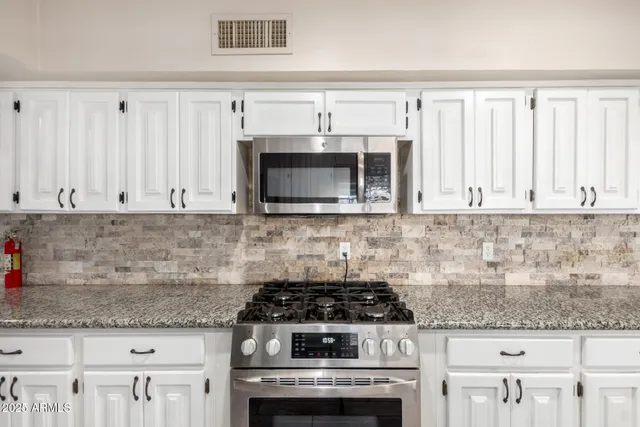 a kitchen with kitchen island granite countertop a sink and white cabinets