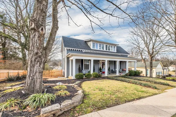 a front view of a house with a yard outdoor seating and large tree
