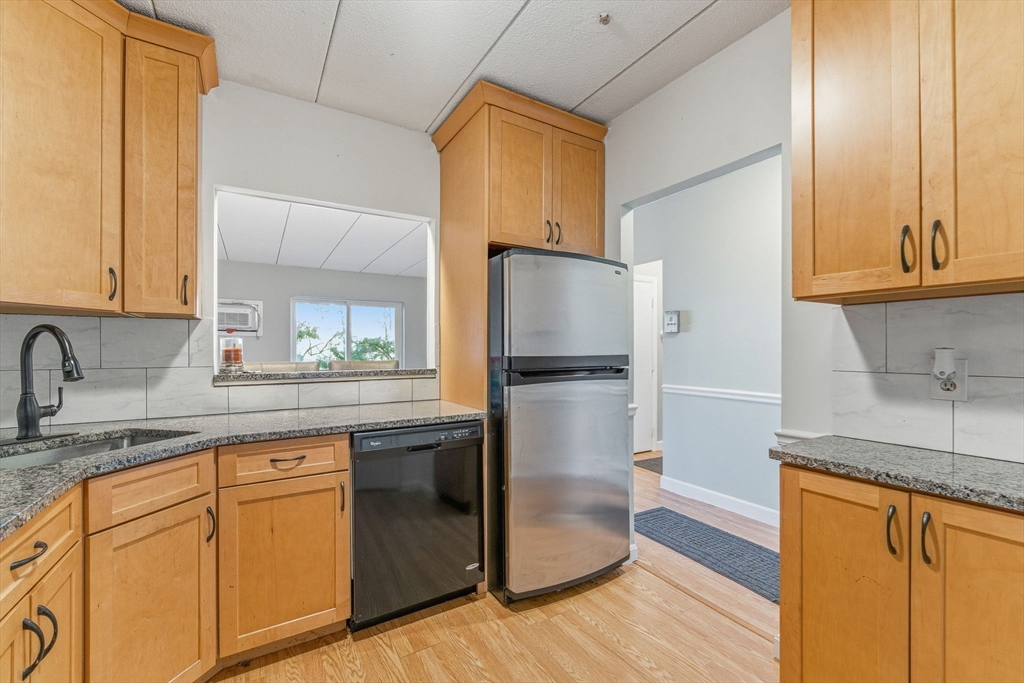 1011 Main Street, Unit 5 Woburn, MA 01801 - Photo 8 of 26 a kitchen with granite countertop a refrigerator and a sink