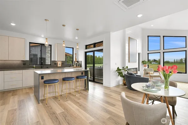 a kitchen with stainless steel appliances kitchen island granite countertop a refrigerator a stove a sink and white cabinets with wooden floor