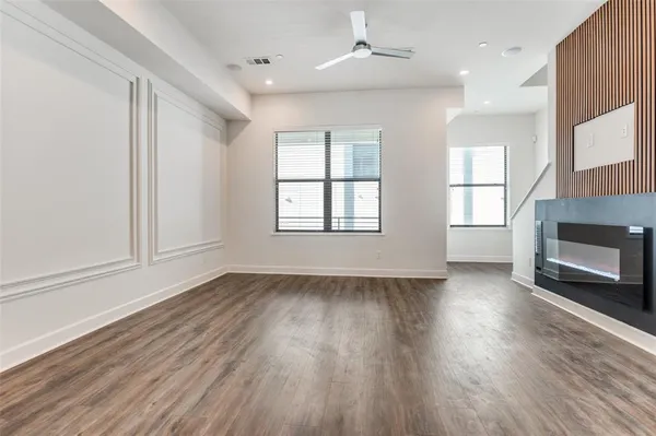 an empty room with wooden floor fireplace and windows