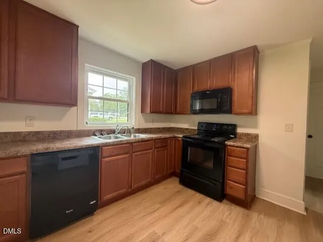 a kitchen with stainless steel appliances granite countertop wooden cabinets a stove a sink and dishwasher with wooden floor