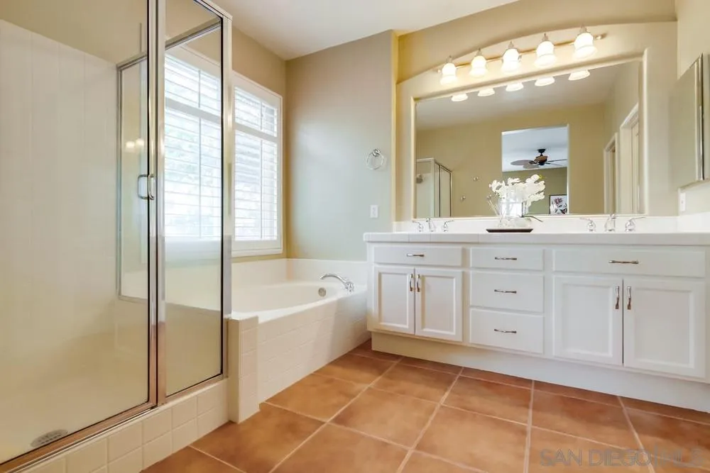 12237 Pepper Tree Lane Poway, CA 92064 - Photo 15 of 25 a spacious bathroom with a double vanity sink a mirror a bathtub and next to a window