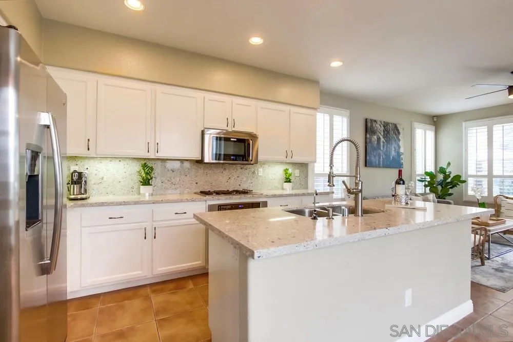 12237 Pepper Tree Lane Poway, CA 92064 - Photo 10 of 25 a kitchen with kitchen island granite countertop a sink a stove cabinets counter top space and stainless steel appliances