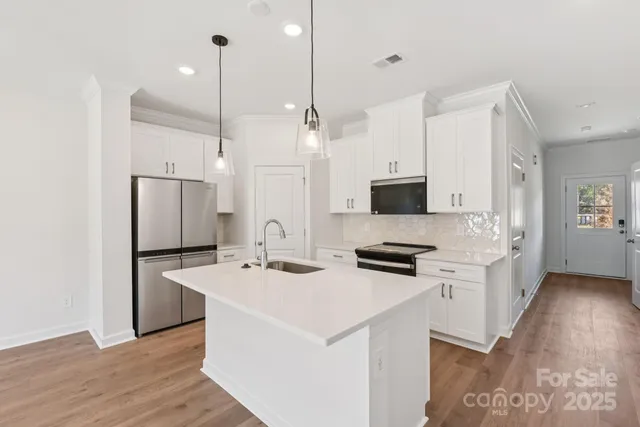 a kitchen with stainless steel appliances a stove top oven a sink a refrigerator a center island and cabinets