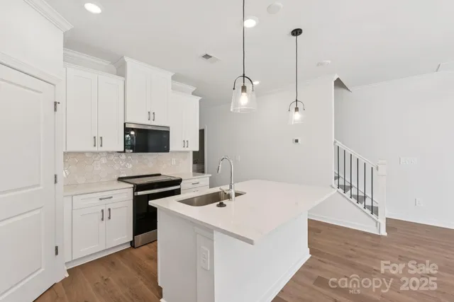 a kitchen with stainless steel appliances a sink a stove a refrigerator and white cabinets