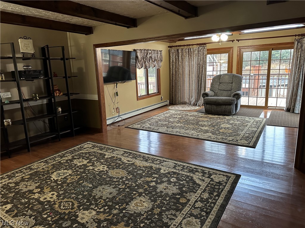 13055 Unity Road New Springfield, OH 44443 - Photo 31 of 49 Living room featuring baseboard heating, beam ceiling, and dark wood-type flooring