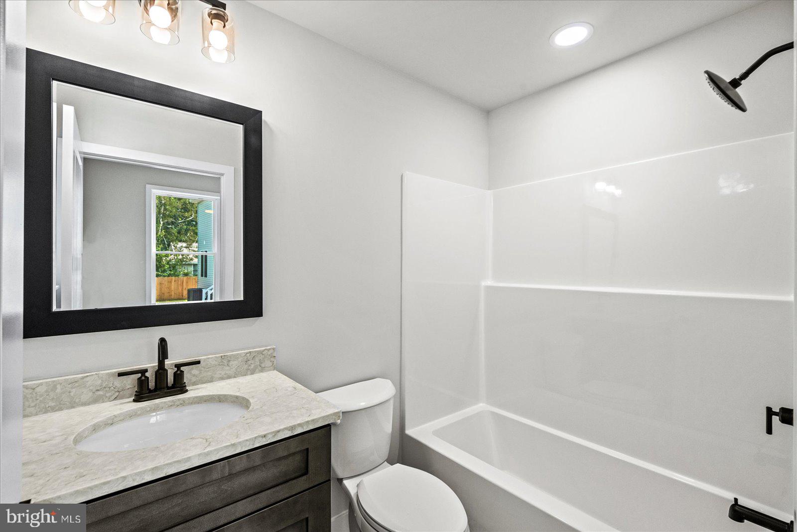 702 Taggart Street Colonial Beach, VA 22443 - Photo 19 of 64 a bathroom with a granite countertop sink toilet a mirror and bathtub