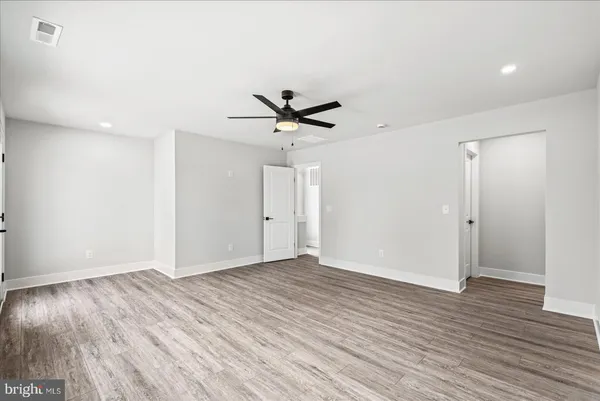 an empty room with wooden floor ceiling fan and windows