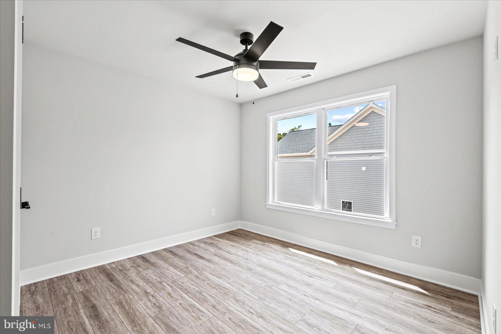 702 Taggart Street Colonial Beach, VA 22443 - Photo 33 of 64 an empty room with wooden floor ceiling fan and windows