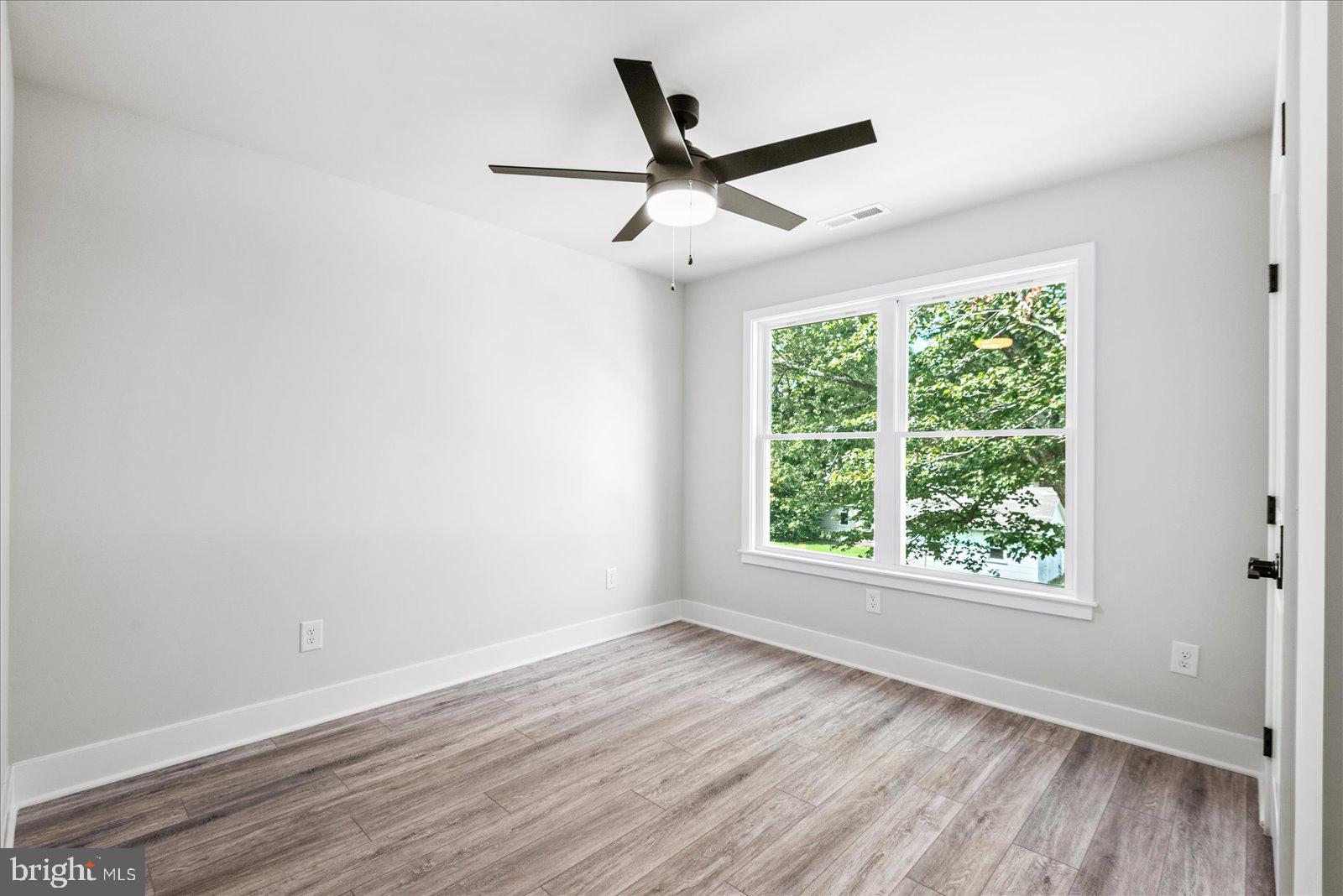 702 Taggart Street Colonial Beach, VA 22443 - Photo 35 of 64 an empty room with wooden floor ceiling fan and windows