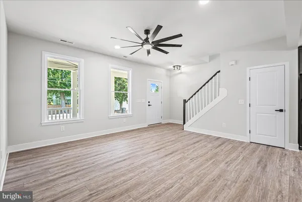 an empty room with wooden floor ceiling fan with window