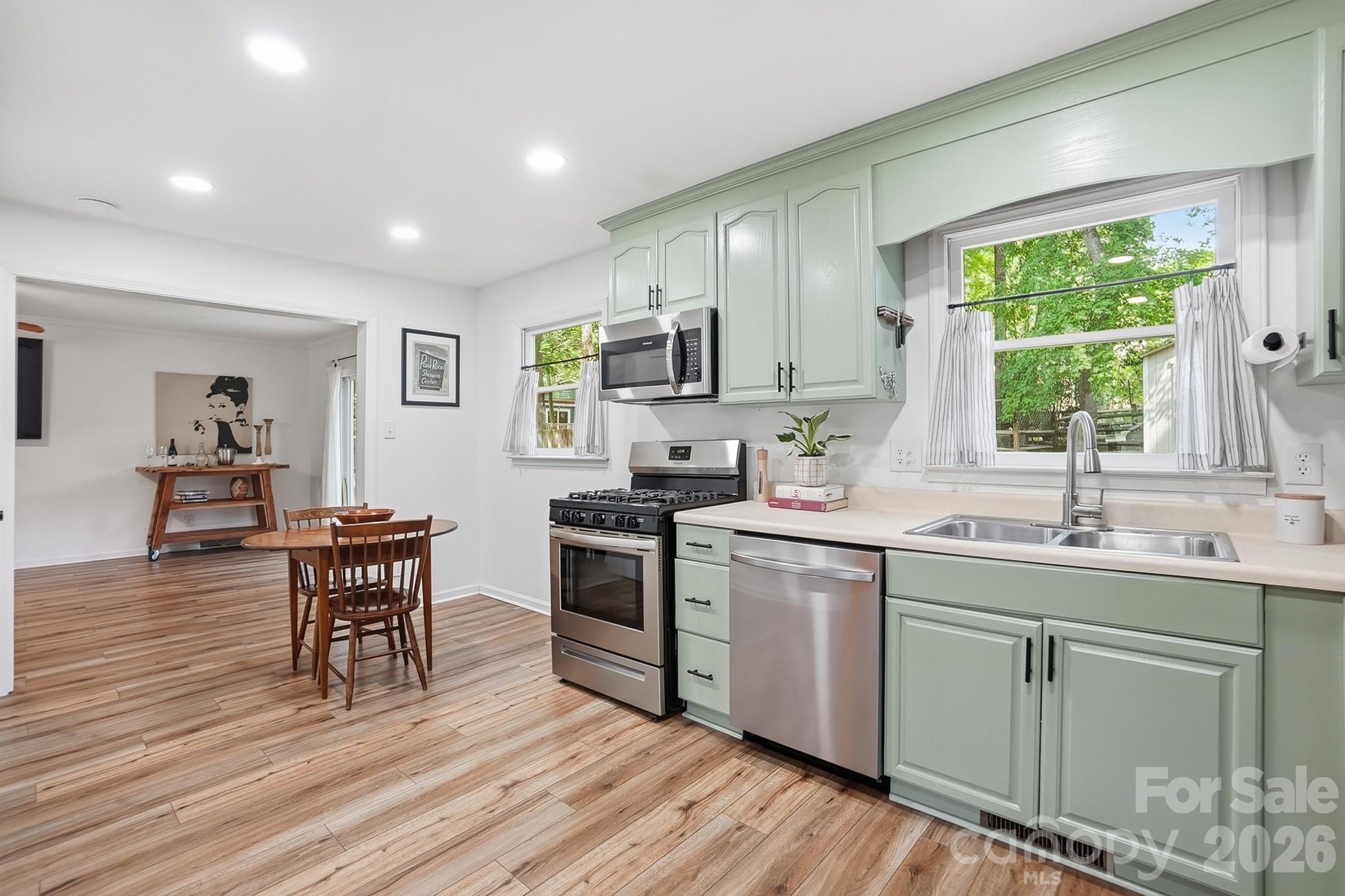 5060 Suwarrow Circle Tega Cay, SC 29708 - Photo 8 of 34 a kitchen with stainless steel appliances granite countertop a stove top oven a sink dishwasher a dining table and chairs with wooden floor