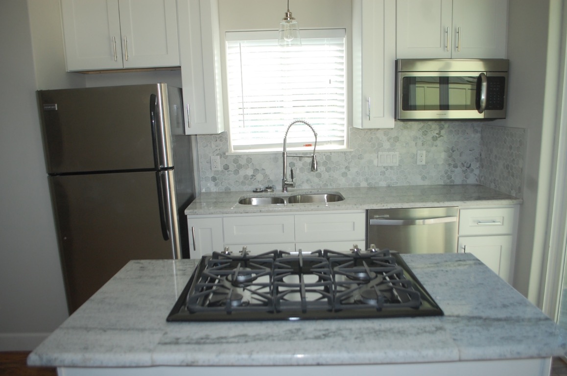 1707 Garden Street, Unit B Austin, TX 78702 - Photo 20 of 33 Kitchen featuring light stone counters, appliances with stainless steel finishes, white cabinetry, a center island, and hanging light fixtures