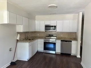a kitchen with granite countertop a sink cabinets and stainless steel appliances
