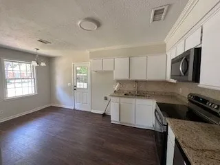 a kitchen with granite countertop a stove and a wooden floors