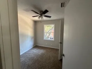 an empty room with windows and fan