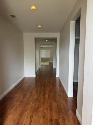 a view of a hallway with wooden floor and a living room