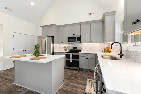 a kitchen with refrigerator a stove a sink and white cabinets with wooden floor