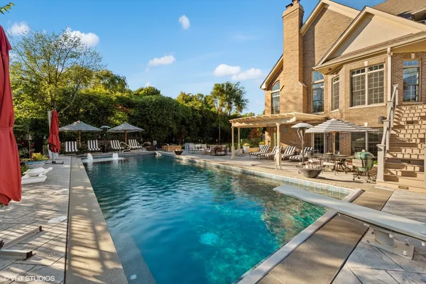 a view of swimming pool with outdoor seating and trees in the background