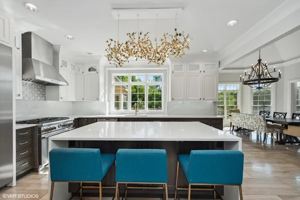 a dining room with wooden floor a chandelier a glass table and chairs