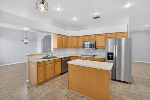 a kitchen with stainless steel appliances granite countertop a refrigerator a sink dishwasher a stove with white cabinets and wooden floor