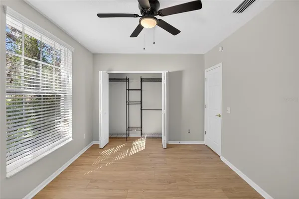 a view of an empty room with chandelier fan and window