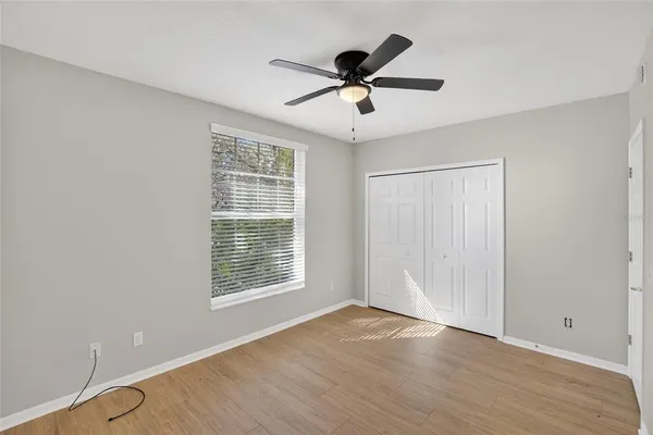 a view of a big room with wooden floor a ceiling fan and windows