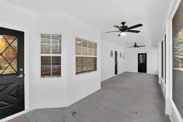a view of empty room with windows and ceiling fan