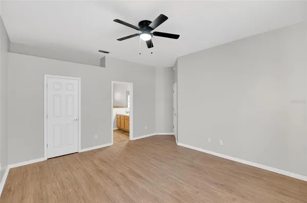 an empty room with wooden floor and ceiling fan