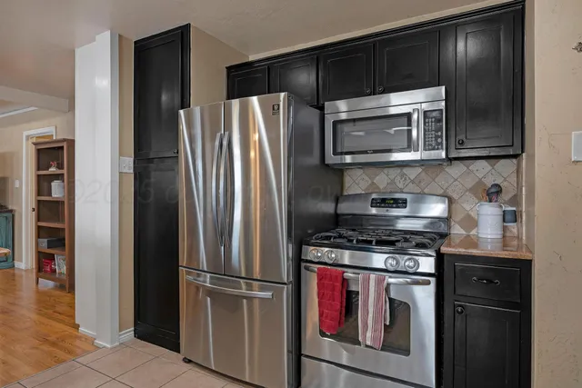 a kitchen with stainless steel appliances granite countertop a refrigerator and a stove top oven