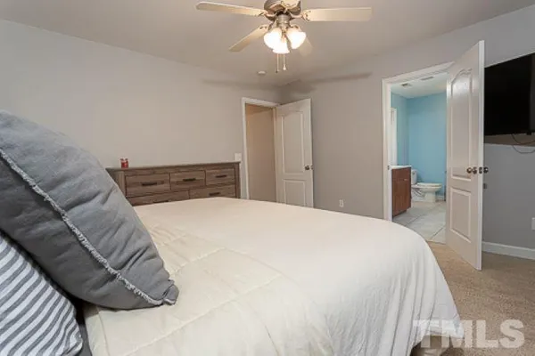 a bedroom with a bed and a flat tv screen on dresser