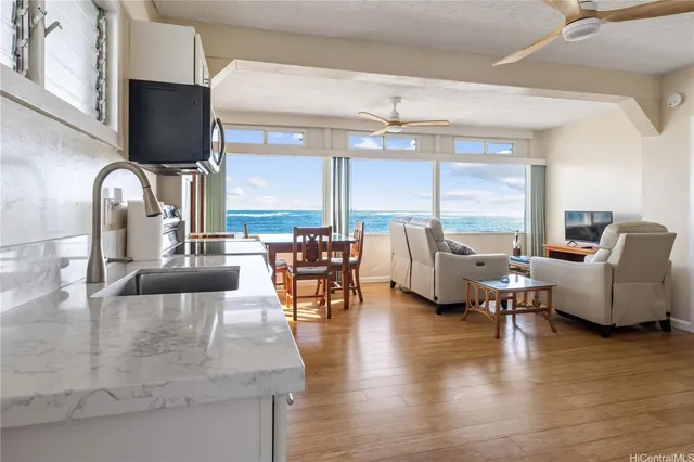 a living room with couches and a flat screen tv with kitchen view