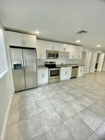 a large kitchen with stainless steel appliances granite countertop a stove a sink and a refrigerator