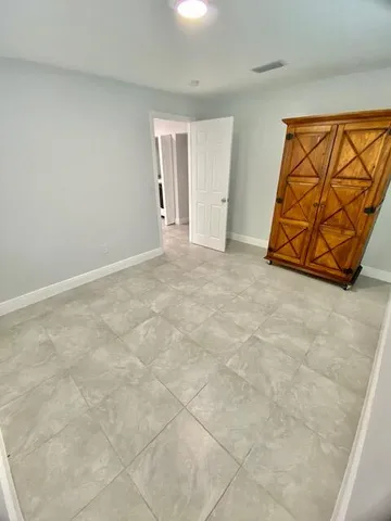 an empty room with a chandelier fan and windows