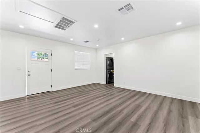 an empty room with wooden floor and natural light