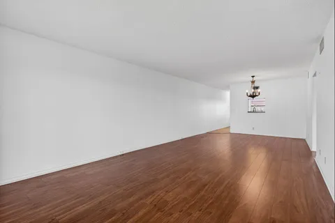 an empty room with wooden floor ceiling fan and windows