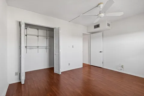 an empty room with wooden floor closet and windows