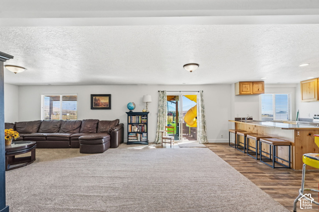 9044 North Cedar Pass Road Eagle Mountain, UT 84005 - Photo 31 of 63 Open-concept living space featuring a carpeted area, wood-finish flooring, a kitchen island with seating, a sliding glass door, and recessed lighting