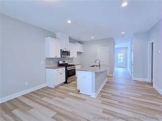 a large kitchen with cabinets wooden floor and stainless steel appliances