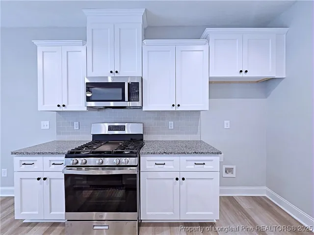 a kitchen with granite countertop white cabinets and stainless steel appliances