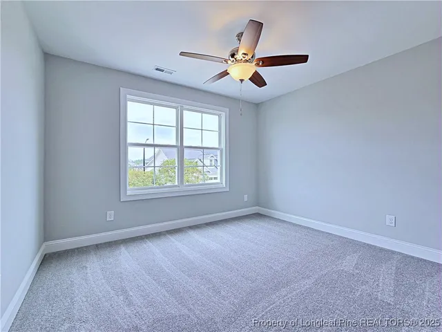 an empty room with ceiling fan and windows