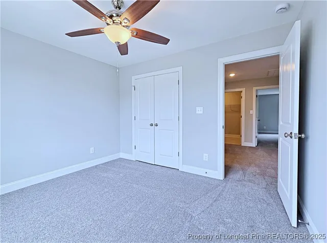 an empty room with closet and a chandelier fan