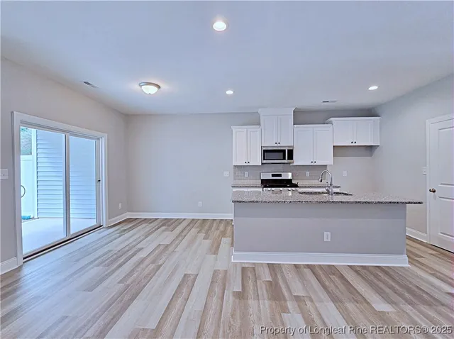 a kitchen with granite countertop wooden floors stainless steel appliances and sink