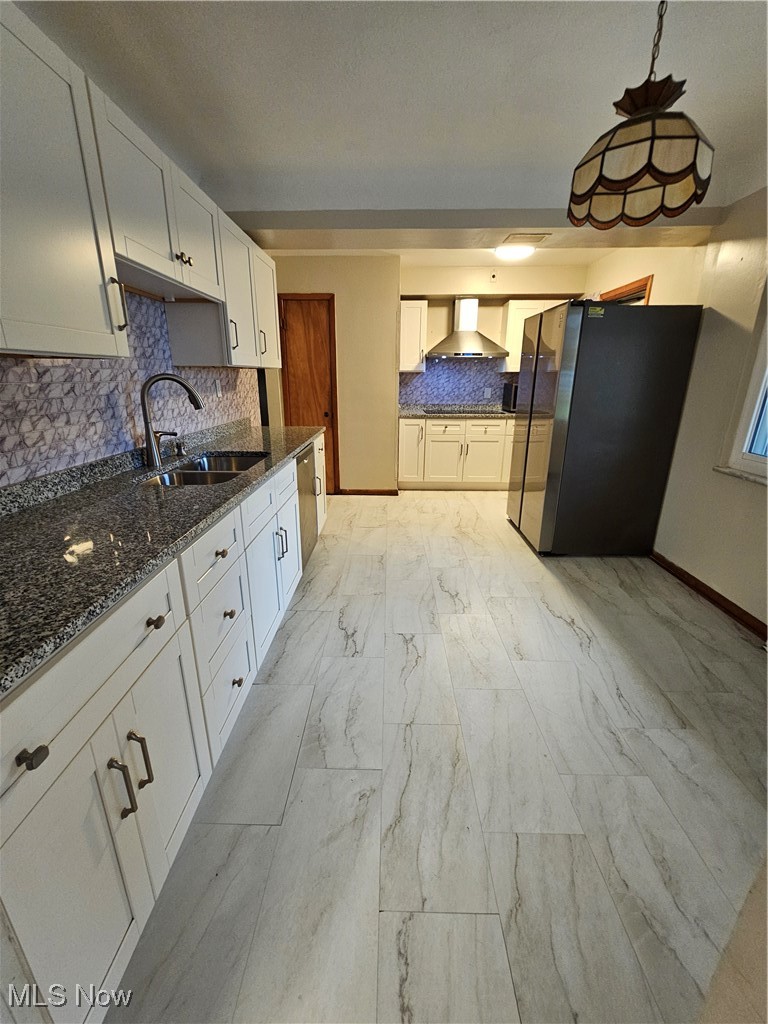 Kitchen with white cabinetry, refrigerator, pendant lighting, and range hood