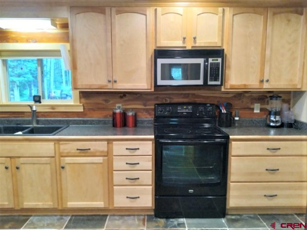 100 Crest Drive Cimarron, CO 81220 - Photo 9 of 35 a kitchen with granite countertop white cabinets and stainless steel appliances