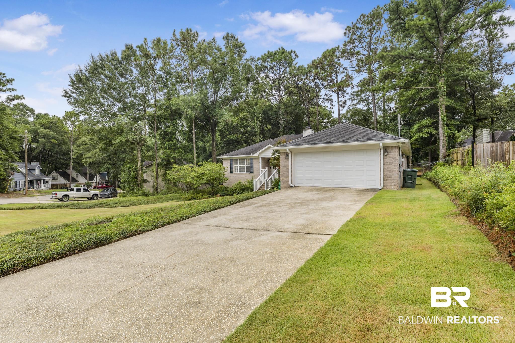 140 Hope Drive Daphne, AL 36526 - Photo 45 of 54 Ranch-style house featuring brick siding, driveway, a garage, a chimney, and view of scattered trees