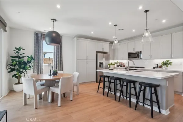 a kitchen with stainless steel appliances kitchen island granite countertop a dining table chairs and white cabinets